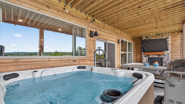 A hot tub area with a stone fireplace and a view of the outdoors. - Luxe 4BR-4BA, Branson Retreat with Lake Views, Pools + Pickleball (Branson)