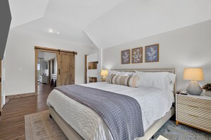 Ein Schlafzimmer mit einem großen Bett, Nachttischlampen und einer Holztür.