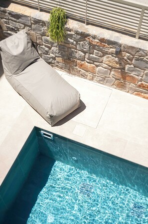A poolside area with a lounge chair and a stone wall. - Villa Penelope, Heraklion, Crete, Gazi (Gazi)