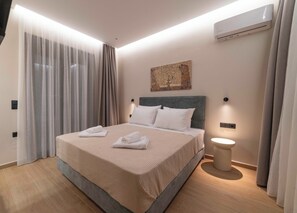 A modern hotel room with a large bed, a bedside table, an air conditioning unit, and a painting on the wall. - Villa Penelope, Heraklion, Crete, Gazi (Gazi)