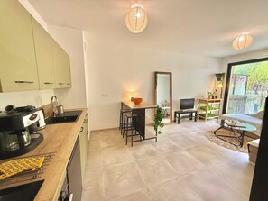 A modern kitchen with a dining area, a TV, and a large window. - Charming retreat in downtown Aix-en-Provence — Private garden & parking (Aix-en-Provence)