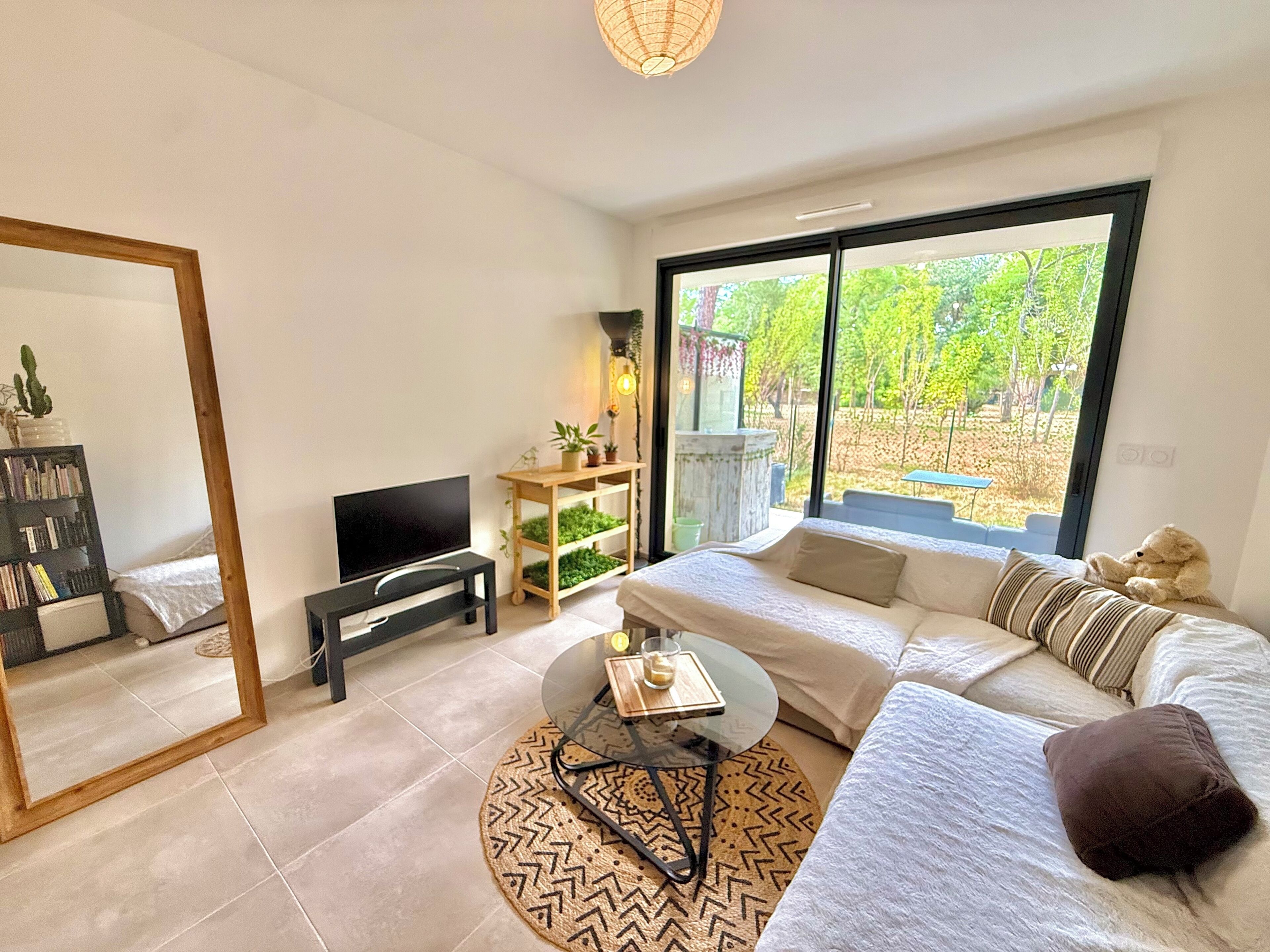 A modern living room with a large window, a sofa, a coffee table, a TV, and a bookshelf.