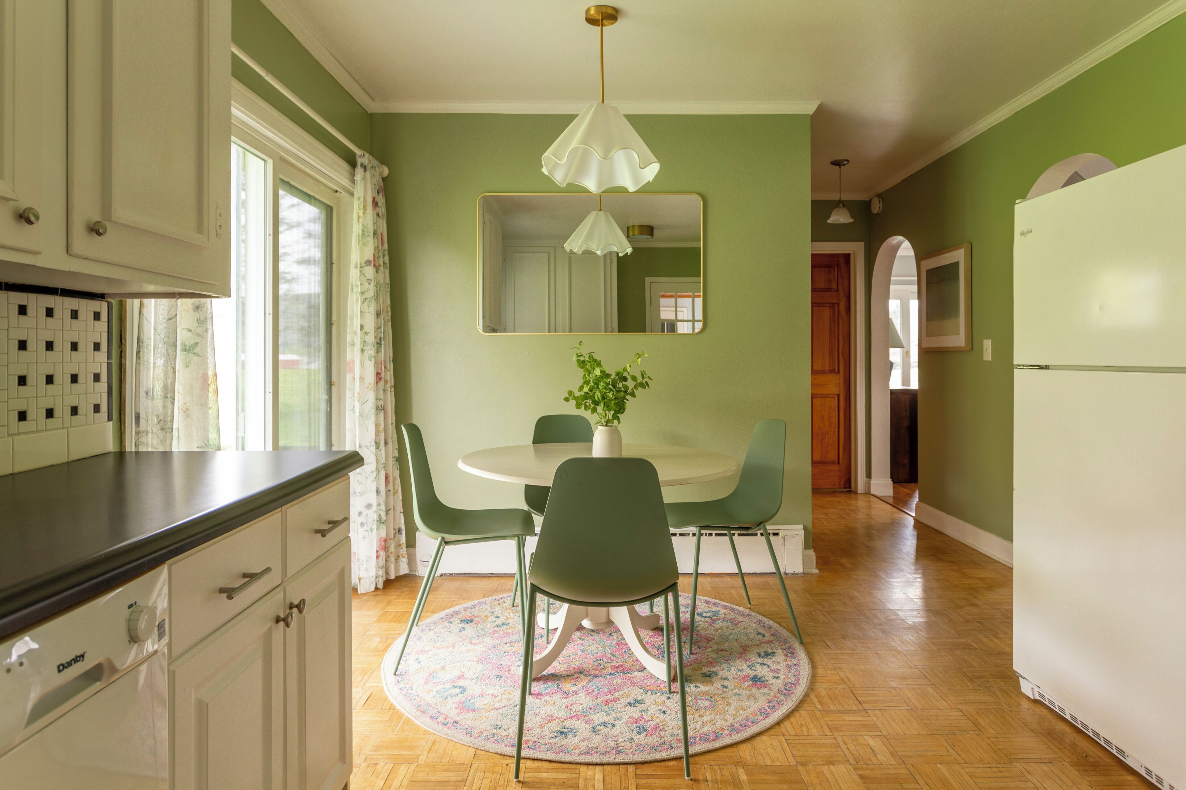 Una cocina con una mesa de comedor, sillas, una planta en maceta y un espejo en la pared.