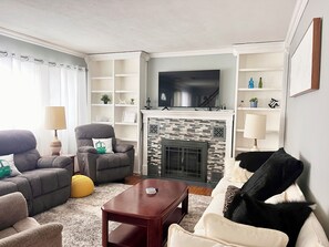 Una sala de estar con chimenea, sofás, una mesa de centro y un televisor.