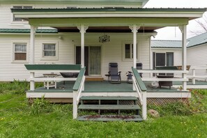 Eine Veranda mit zwei Stühlen, einem Tisch, einer Tür und ein paar Stufen.