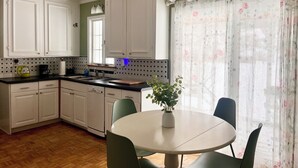 A kitchen with white cabinets, a coffee maker, and a sink. There is a round table with chairs and a potted plant. - Gorgeous 5-bedroom house in welcoming Ellicottville perfect for families (Ellicottville)