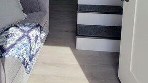 A modern interior with a staircase leading to a kitchen area, a sofa with a patterned throw, and a ceiling fan. - Cozy 1-bedroom tiny house in beautiful Parkersburg,WV (Parkersburg)
