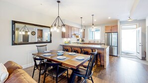 Una cocina moderna con comedor, piso de madera y un espejo grande.