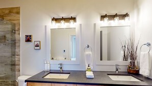 Un baño moderno con dos lavamanos, un espejo grande y armarios de madera.