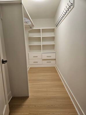 A narrow hallway with a wooden floor, white walls, and a white storage unit with shelves and drawers. - Luxe 4BD family retreat w/AC, Yard, Bunks and King (Calgary)