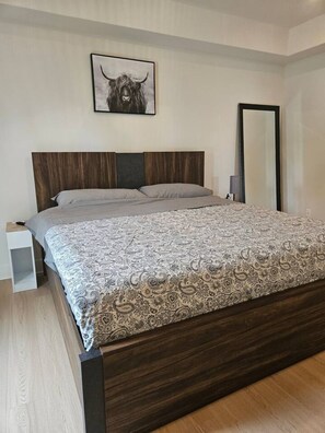 A bedroom with a bed, a nightstand, a mirror, and a wall-mounted picture. - Luxe 4BD family retreat w/AC, Yard, Bunks and King (Calgary)