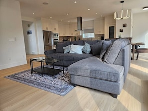 A modern living room with a sectional sofa, a glass coffee table, and a patterned rug. - Luxe 4BD family retreat w/AC, Yard, Bunks and King (Calgary)