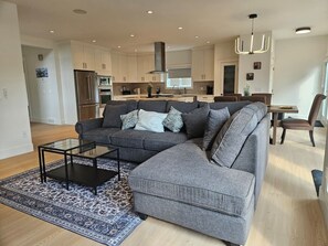 A modern living room with a sectional sofa, a glass coffee table, and a patterned rug. - Luxe 4BD family retreat w/AC, Yard, Bunks and King (Calgary)