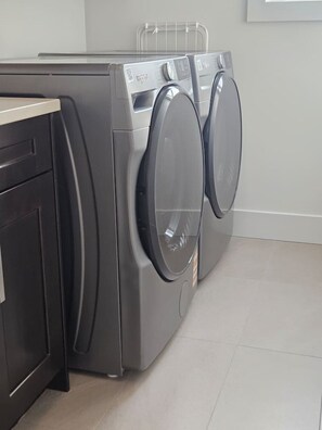 A modern laundry room with two front-loading washing machines and a built-in dryer. - Luxe 4BD family retreat w/AC, Yard, Bunks and King (Calgary)