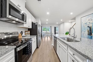 A modern kitchen with stainless steel appliances, granite countertops, and a view to the dining area. - Modern 3BR Townhome- Perfect for Short/Long Stays- Vacation or Traveling Pros! (Myrtle Beach)