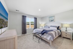 A bedroom with a bed, bedside tables, a window with curtains, a wall-mounted artwork, and a carpeted floor. - Modern 3BR Townhome- Perfect for Short/Long Stays- Vacation or Traveling Pros! (Myrtle Beach)