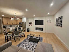 Ein modernes Wohnzimmer mit Essbereich, Kamin und Wandfernseher.
