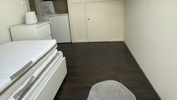 Ein Schlafzimmer mit Oberlicht, einem Bett, einem Kleiderschrank und einer kleinen Küchenzeile.