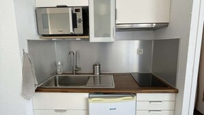 Eine kleine Küche mit Mikrowelle, Spüle und kleinem Kühlschrank.