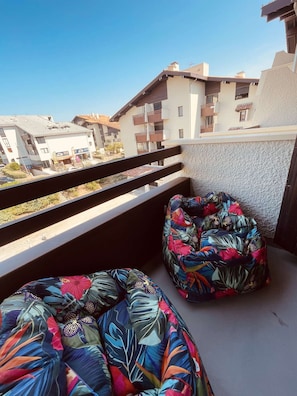 A balcony with two colorful bean bags, a view of residential buildings, and a clear sky. - Bright apartment with 2 balconies – family-friendly – Beach and shops within walking distance (SEIGNOSSE)