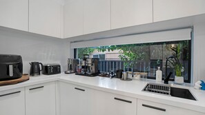 A modern kitchen with white cabinets, a coffee machine, a toaster, and a kettle. - Salt & Spa Norah Head (Norah Head)