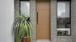 A modern building with a brown door, a large window, and a potted plant. - Salt & Spa Norah Head (Norah Head)