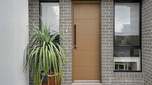 A modern building with a brown door, a large window, and a potted plant. - Salt & Spa Norah Head (Norah Head)
