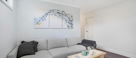 A modern living room with a grey sectional sofa, a wooden coffee table with decorative items, and abstract wall art.