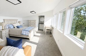 Un dormitorio con cama, cómoda, escritorio y vistas a zonas verdes.