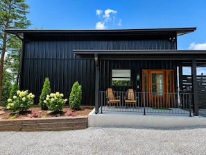 A modern building with a black exterior, a wooden door, and a covered porch with chairs. - Bluff View Overlooking Sequatchie Valley. 2 King Beds + Hot Tub (Graysville)