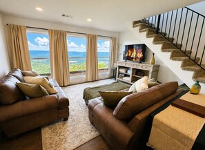 A living room with leather sofas, a flat-screen TV, a fireplace, and a staircase. - Bluff View Overlooking Sequatchie Valley. 2 King Beds + Hot Tub (Graysville)