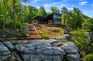 A modern house with a wooden deck, a stone pathway, and a view of the surrounding forest. - Bluff View Overlooking Sequatchie Valley. 2 King Beds + Hot Tub (Graysville)