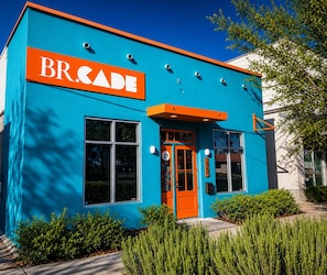 Un edificio con fachada azul y detalles naranja, que destaca un cartel con la leyenda 'BRCADE'.