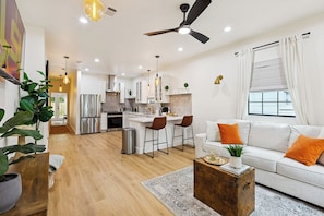 Una cocina moderna con armarios blancos, un refrigerador de acero inoxidable y una zona de comedor con taburetes de bar.