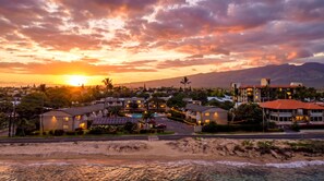 A coastal resort with beachfront properties, a swimming pool, and a view of the sunset over the ocean. - Kihei Holiday 215 (Kihei)