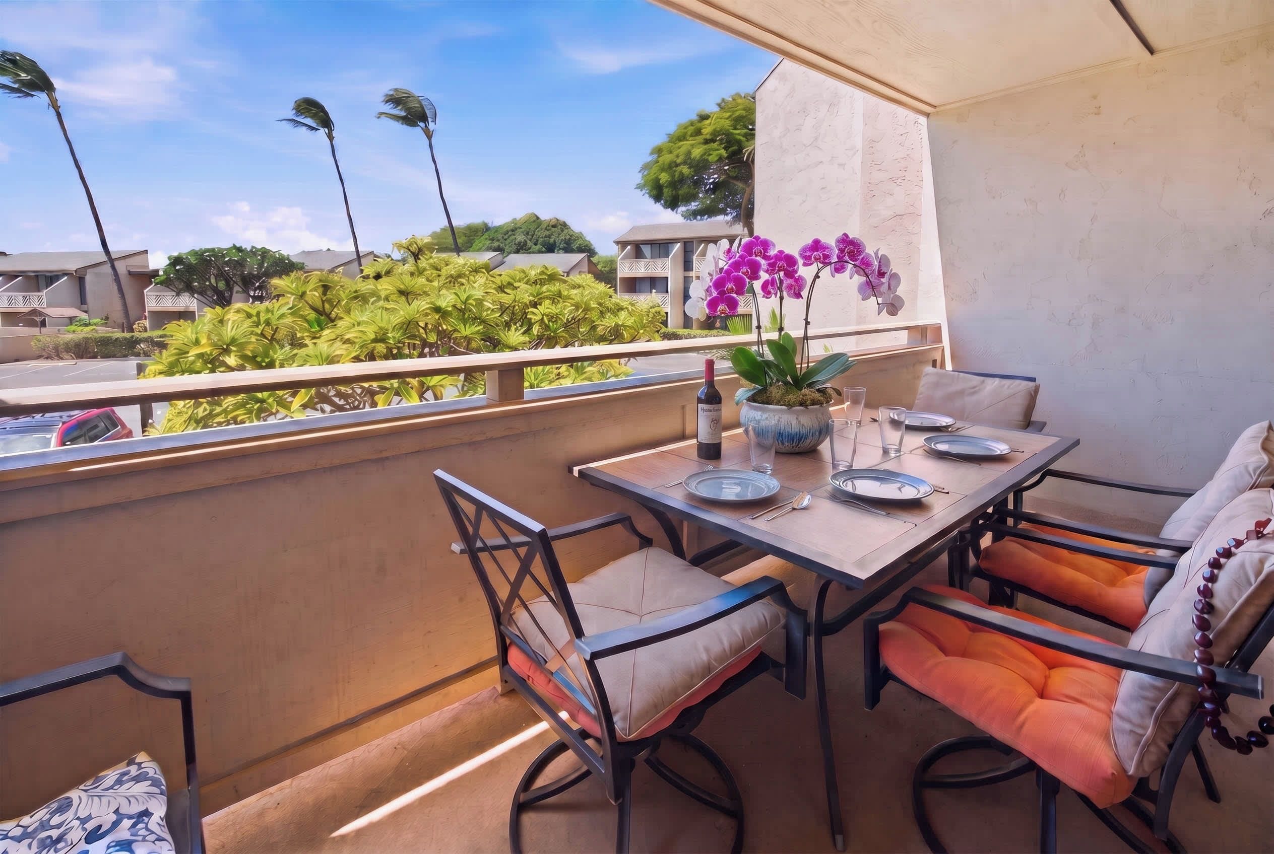A balcony with a table set for dining, chairs, and a potted orchid.