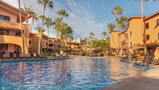 Ein Swimmingpool, umgeben von Palmen und Hotelgebäuden.