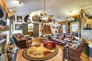 A cozy living room with leather furniture, a round rug with animal prints, and various wall decorations including taxidermy and paintings. - 2 King suites, pool table, hot tub, minutes to downtown Gatlinburg & nat'l park (Gatlinburg)