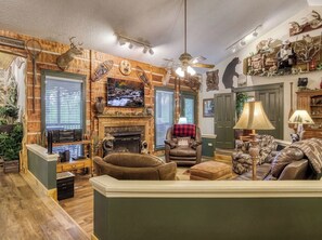A cozy living room with a fireplace, leather furniture, and wall-mounted decor. - 2 King suites, pool table, hot tub, minutes to downtown Gatlinburg & nat'l park (Gatlinburg)