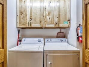 A laundry room with two front-loading washing machines, wooden cabinets above, and a fire extinguisher on the wall. - 2 King suites, pool table, hot tub, minutes to downtown Gatlinburg & nat'l park (Gatlinburg)
