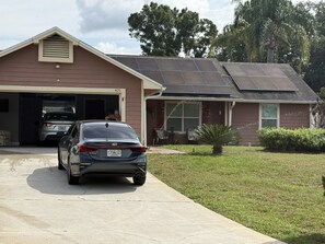 A residential house with a garage, a driveway, and solar panels on the roof. - Phenomenal 3-bedroom house with AC in charming Kissimmee w/heated pool & lanai (Kissimmee)