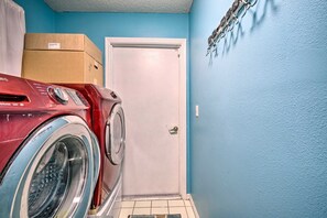 A laundry room with a red washing machine, a white door, and blue walls. - Phenomenal 3-bedroom house with AC in charming Kissimmee w/heated pool & lanai (Kissimmee)