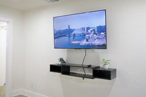 Ein an der Wand befestigter Fernseher, auf dem eine Stadtsicht und eine Sportveranstaltung zu sehen sind.