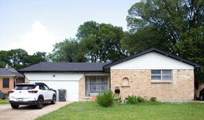 Eingeschossiges Haus mit Garage, Backsteinfassade und kleinem Vorgarten.