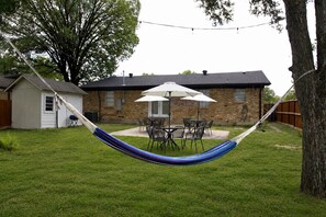 A hammock in a backyard with a brick house, a white garage, and a tree. - 4BR Home Perfect for State Fair of TX (Dallas)