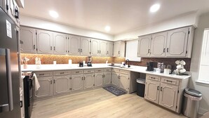 Cozinha moderna com armários de madeira clara, bancada branca e painel de azulejos.