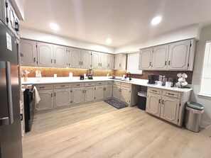 Eine moderne Küche mit hellen Holzschränken, einer weißen Arbeitsplatte und einer gefliesten Spritzschutzwand.