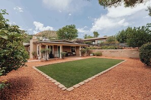 Ein Haus mit überdachter Terrasse, Rasen und gepflegtem Schotterweg.