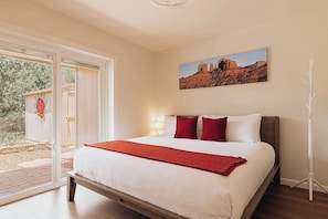 A bedroom with a bed, a painting, and a white coat rack. - Charming Home w/ Casita, Hot Tub, Red Rock Views (Sedona)