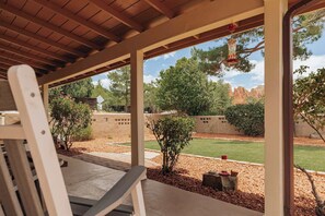 A covered patio with a view of a landscaped garden and distant rock formations. - Charming Home w/ Casita, Hot Tub, Red Rock Views (Sedona)